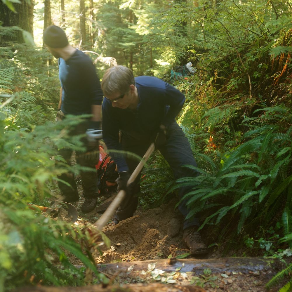 Alexis looking back and Doug digging out to lay a new sleeper into the trail